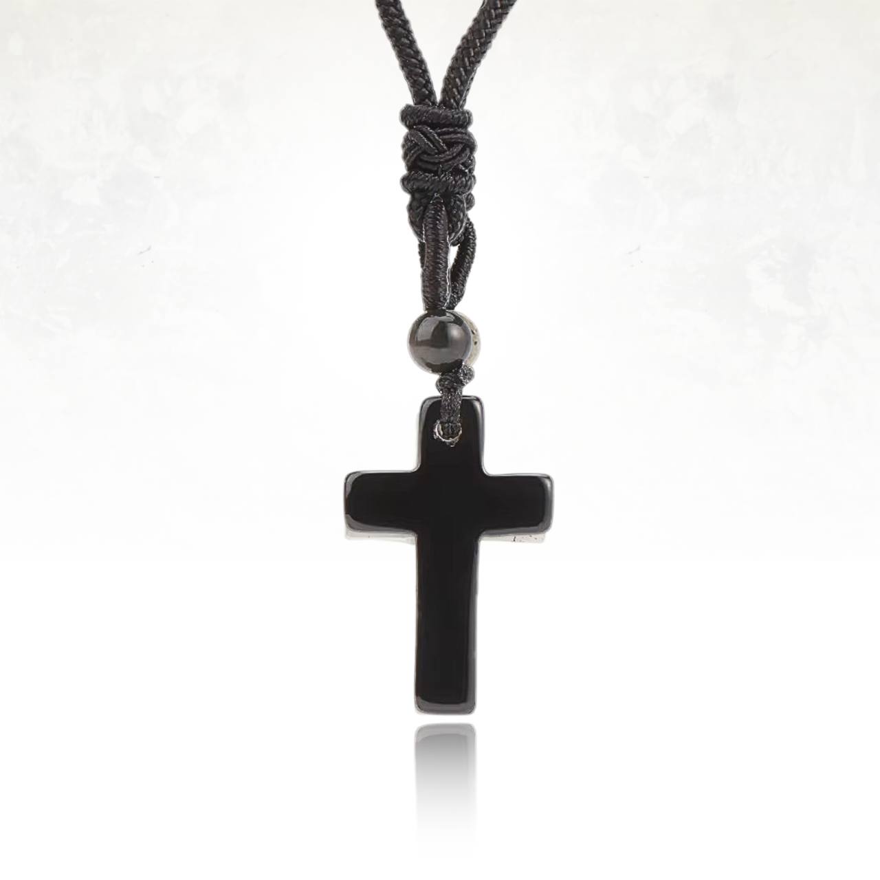 Pendentif croix en pierre naturelle, monté sur un cordon tressé.