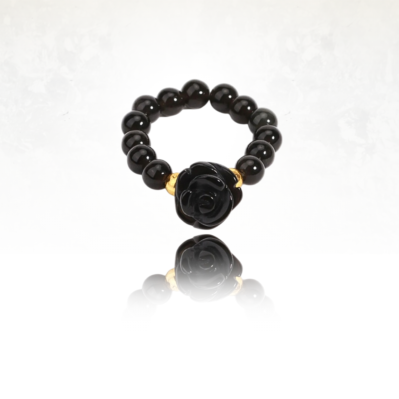 Bague féminine en obsidienne avec une rose taillée et détails dorés.