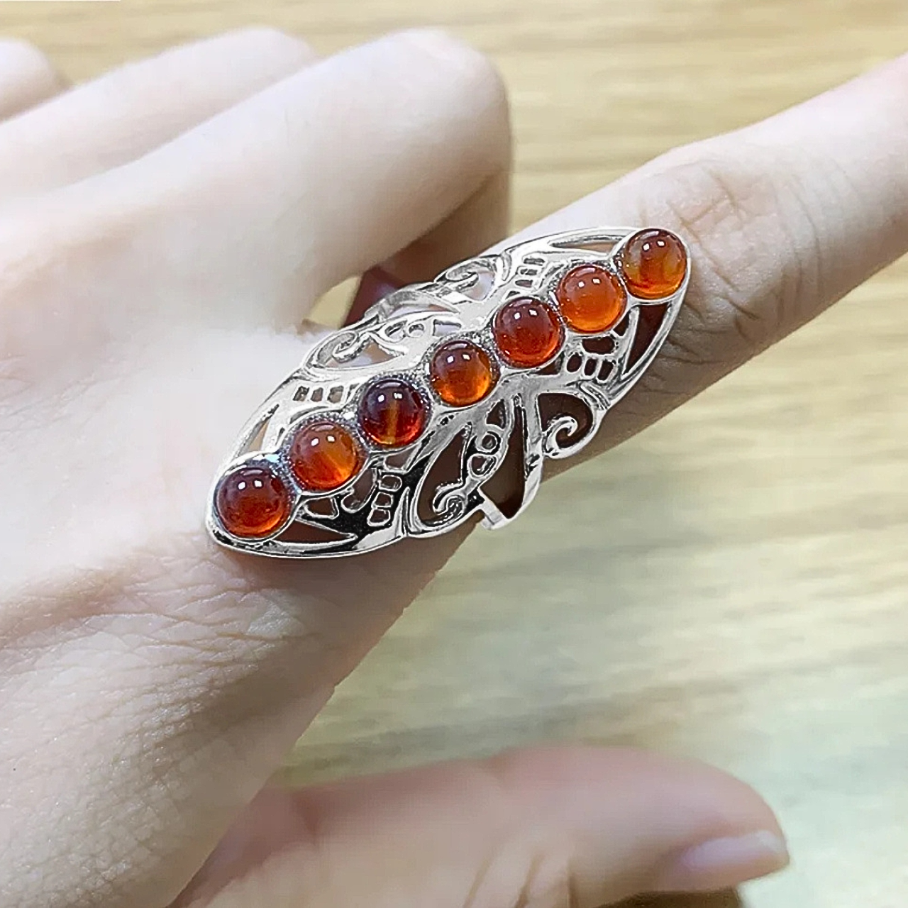 Élégante bague ajourée décorée de 7 perles rouges naturelles.