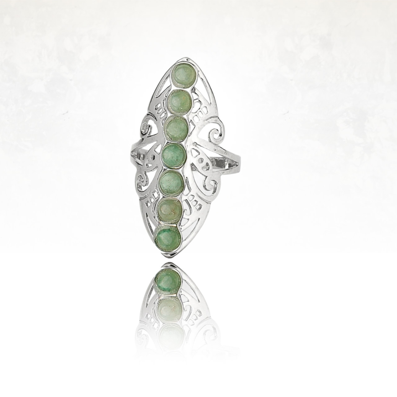 Bague argentée à motif ajouré et sept gemmes vertes polies.