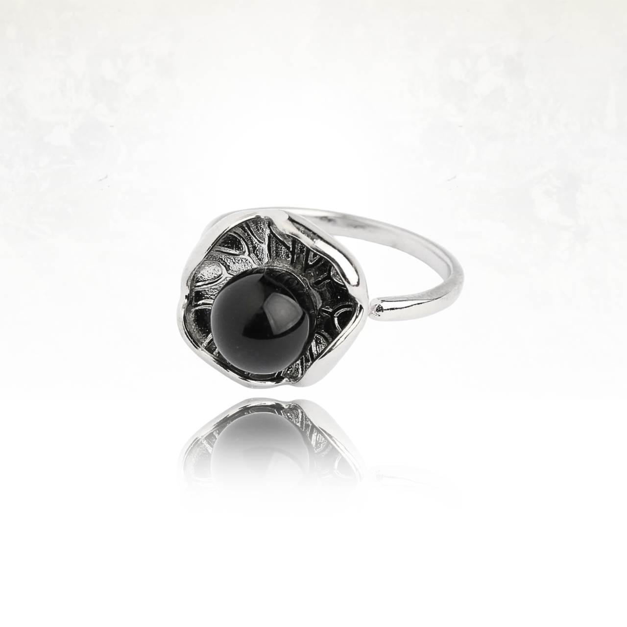 Bague ouverte argentée mettant en valeur un lotus stylisé et une pierre noire.