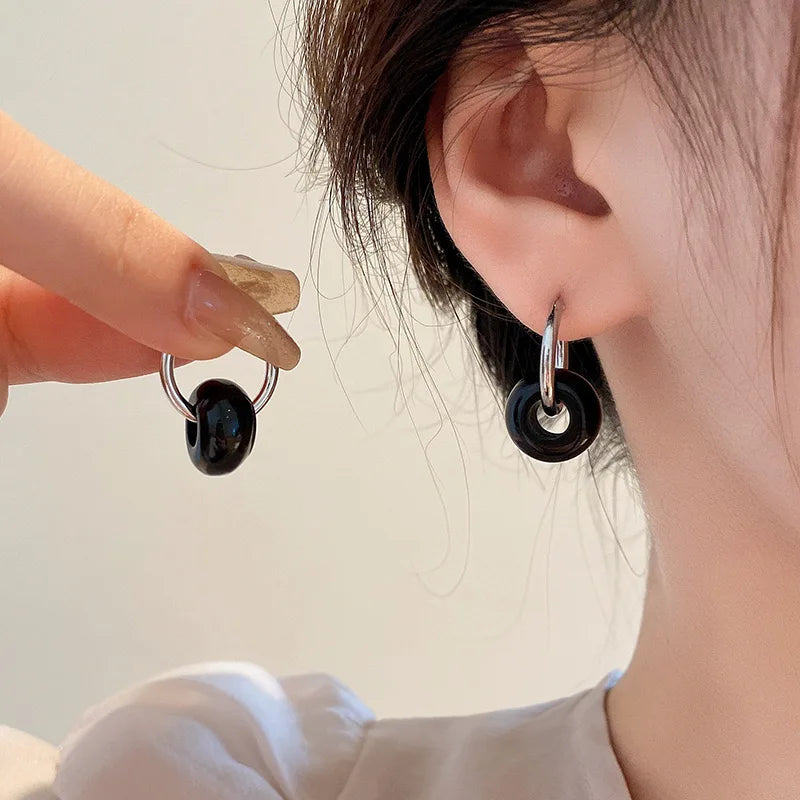 boucles d'oreilles composée d'une perle ronde en obsidienne soutenu par un cerle métallique portée par une femme