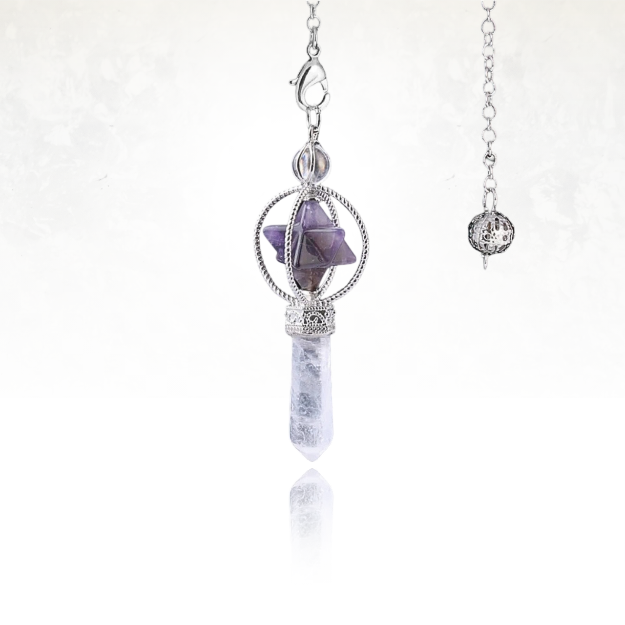 Amulette SINYA composée d’une Merkaba en pierre naturelle d'amethyste et d’une longue pointe en quartz clair translucide.