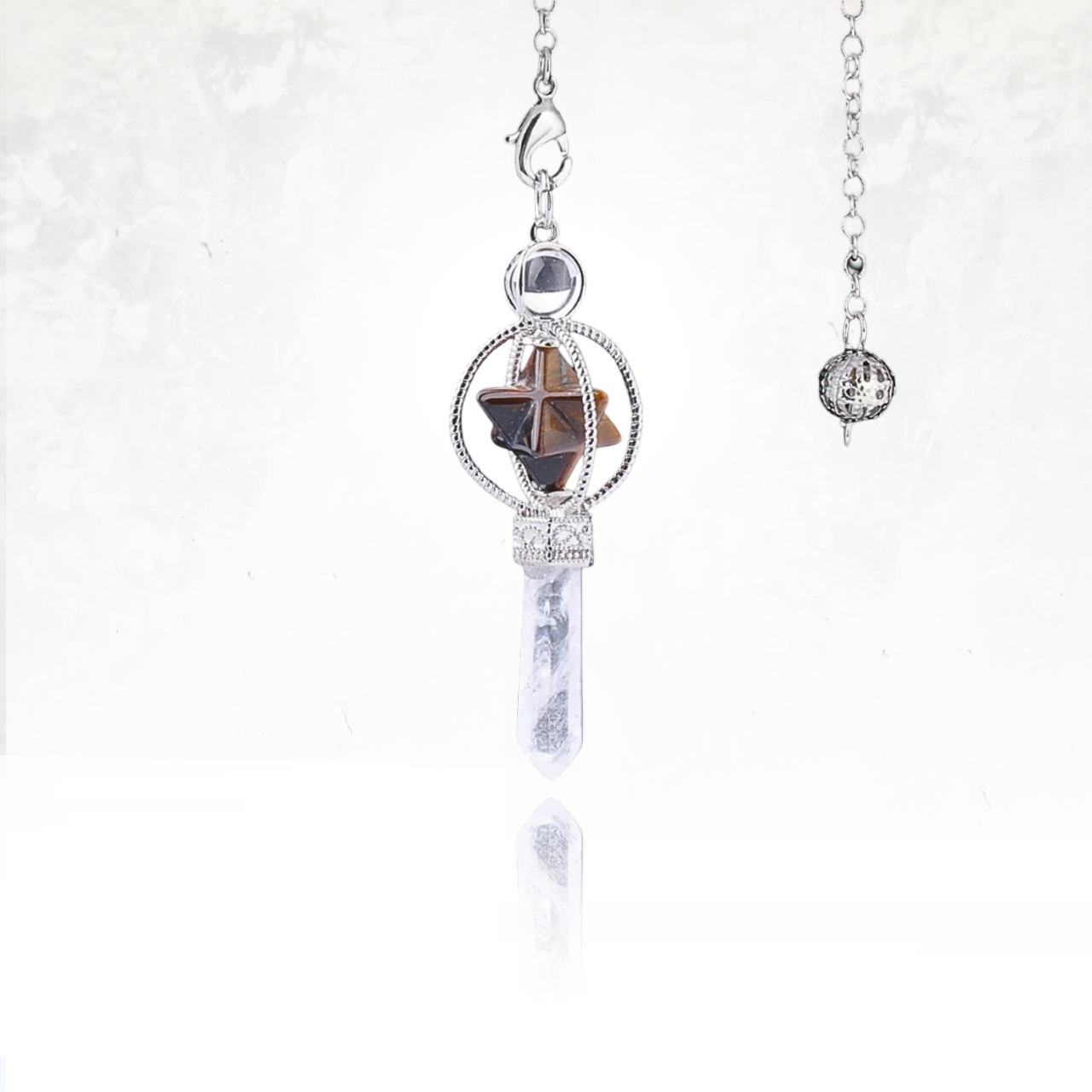 Pendule spirituel SINYA avec Merkaba d'oeil de tigre flottante dans un cadre argenté et pointe en quartz translucide.