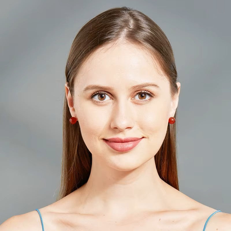 Portrait d’une femme élégante mettant en valeur les boucles d’oreilles rondes en jaspe rouge.