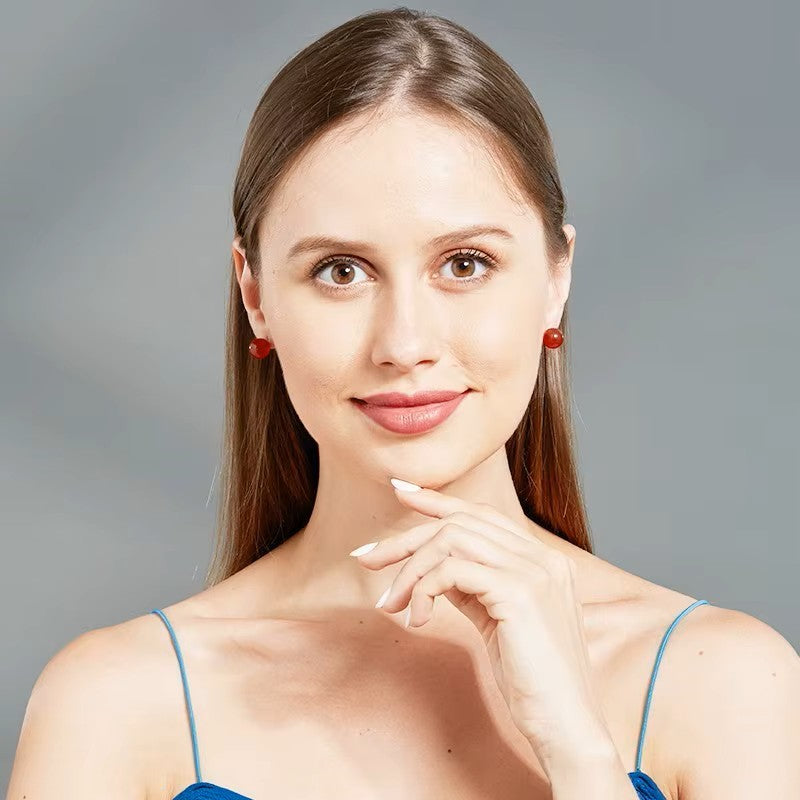 Modèle portant des boucles d’oreilles Salomé, des clous en pierre semi-précieuserouge pour un look raffiné.