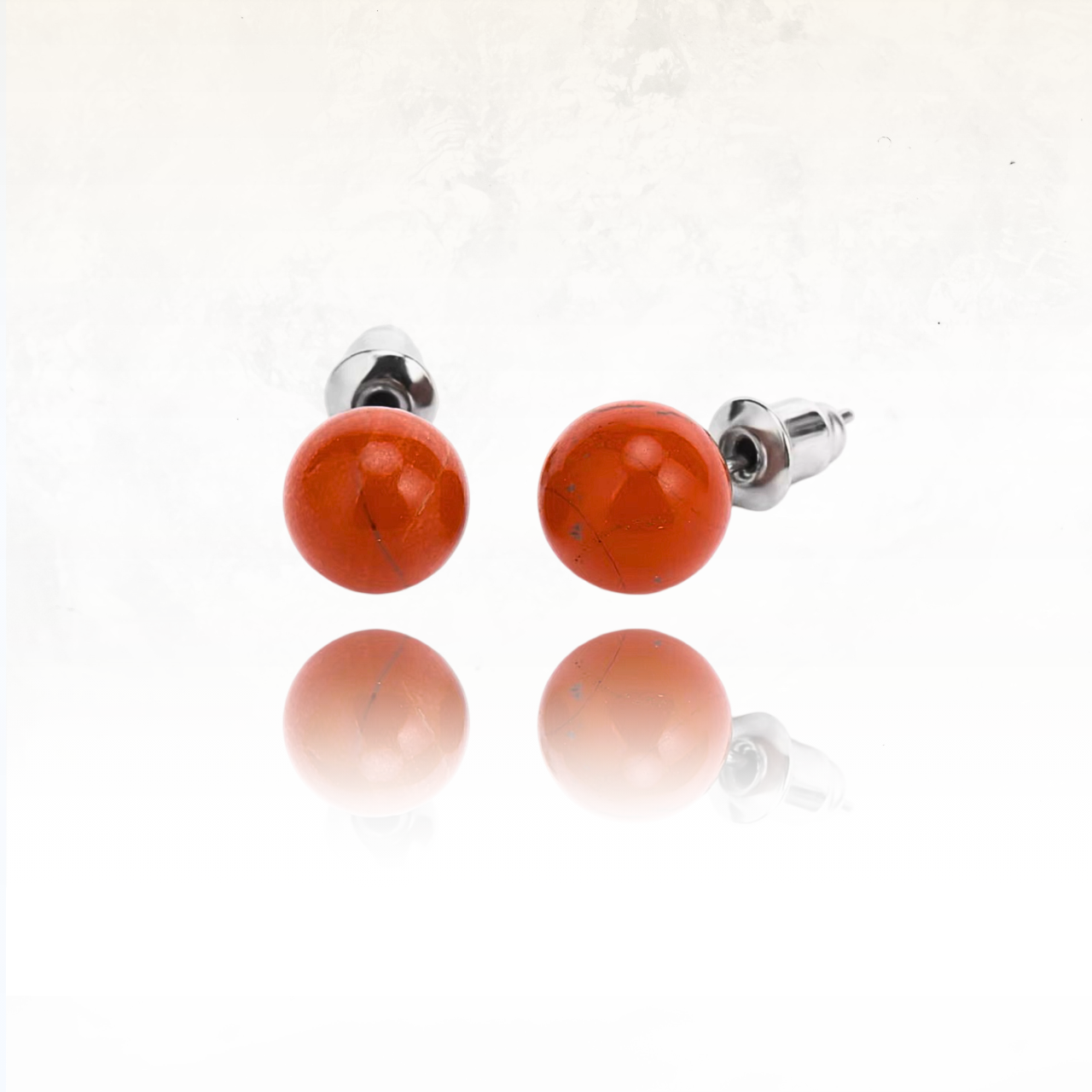 Paire de clous d’oreilles en pierre naturelle aux tons rouges et finition brillante.