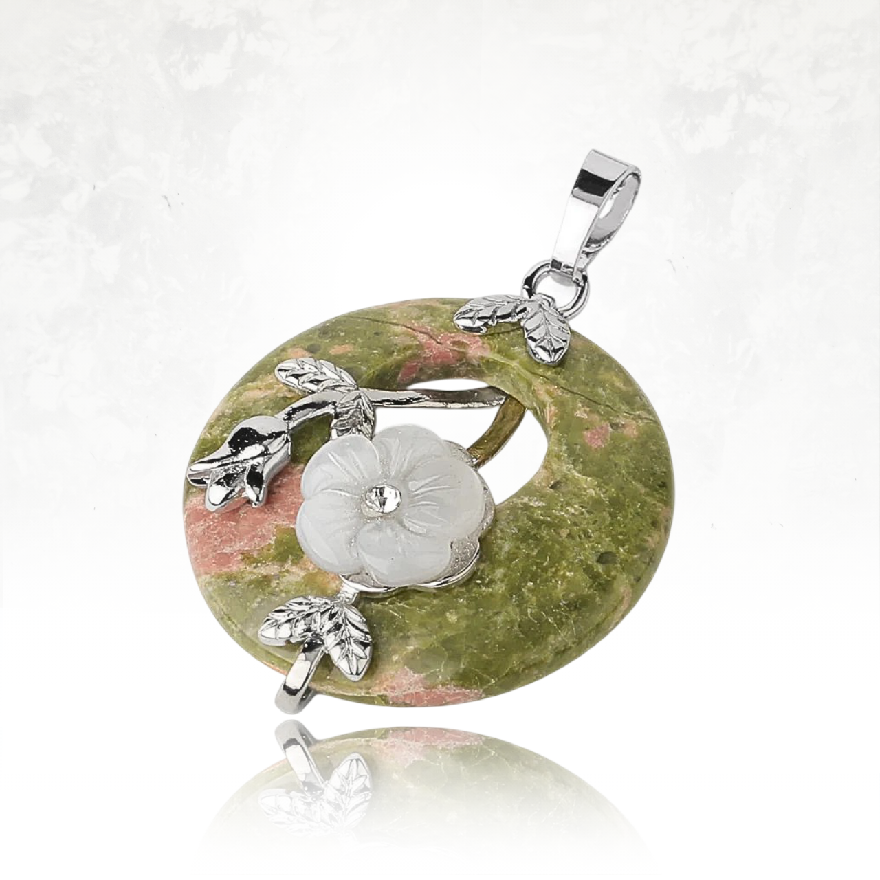 Pendentif en pierre minérale verte et rose orné d’une fleur blanche, symbole de pureté.

